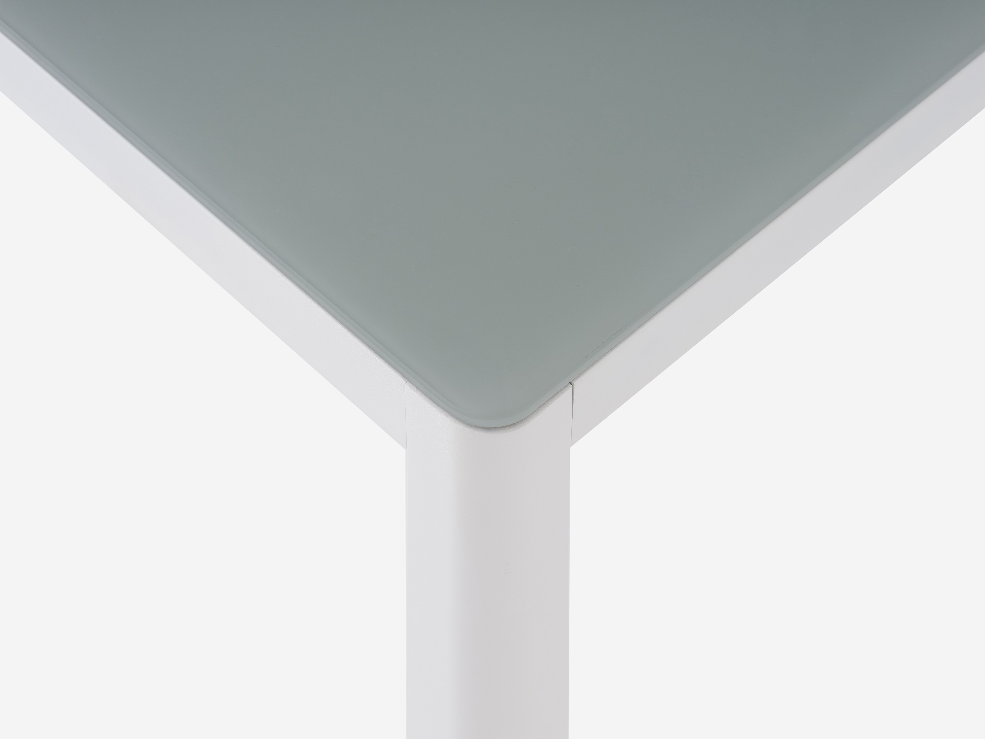 Detail view of the Cape patio dining table with a grey glass top and white metal base